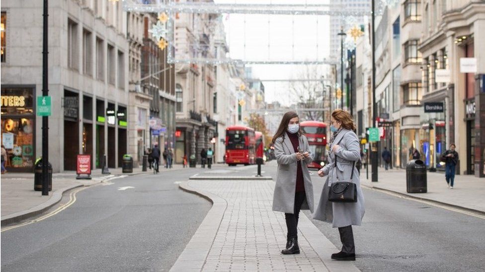 Two people stand in the middle of an empty Oxford Street