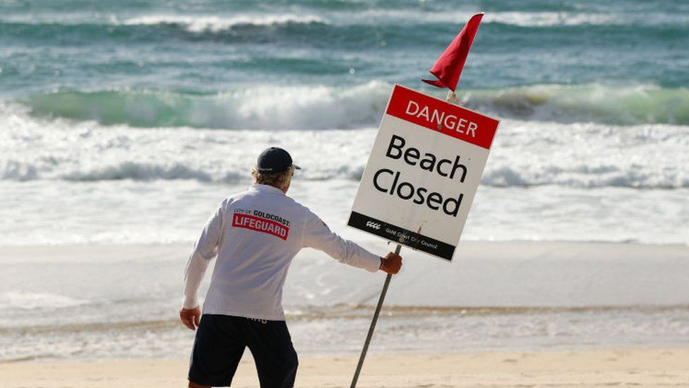 A Gold Coast Lifeguard erects a Beach Closed sign at Surfers Paradise beach on April 08, 2020 in Gold Coast, Australia. A number of major Gold Coast beaches have been closed over COVID-19 concerns.