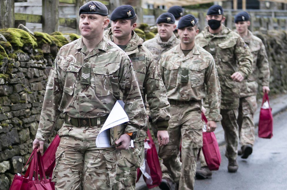 Soldiers carry bags