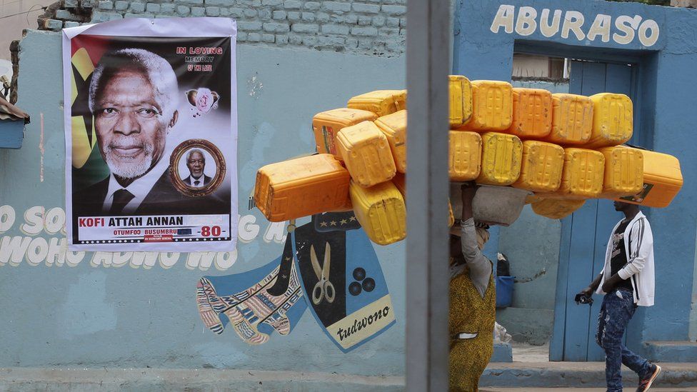 Some carrying jerrycans near a wall with a poster of Kofi Annan in Kumasi, Ghana - Monday 20 August 2018