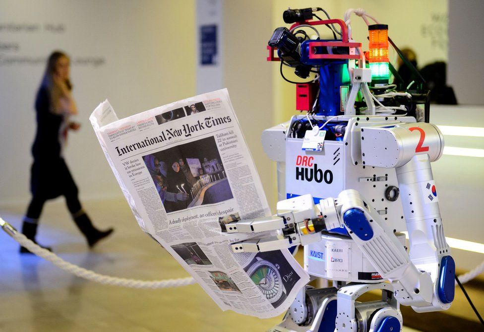 A robot holds a newspaper during a demonstration during the World Economic Forum (WEF) annual meeting in Davos, on January 22, 2016.