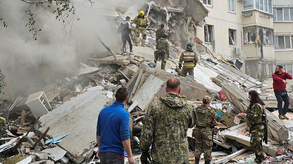 Emergency personnel climb on rubble after apartment collapse