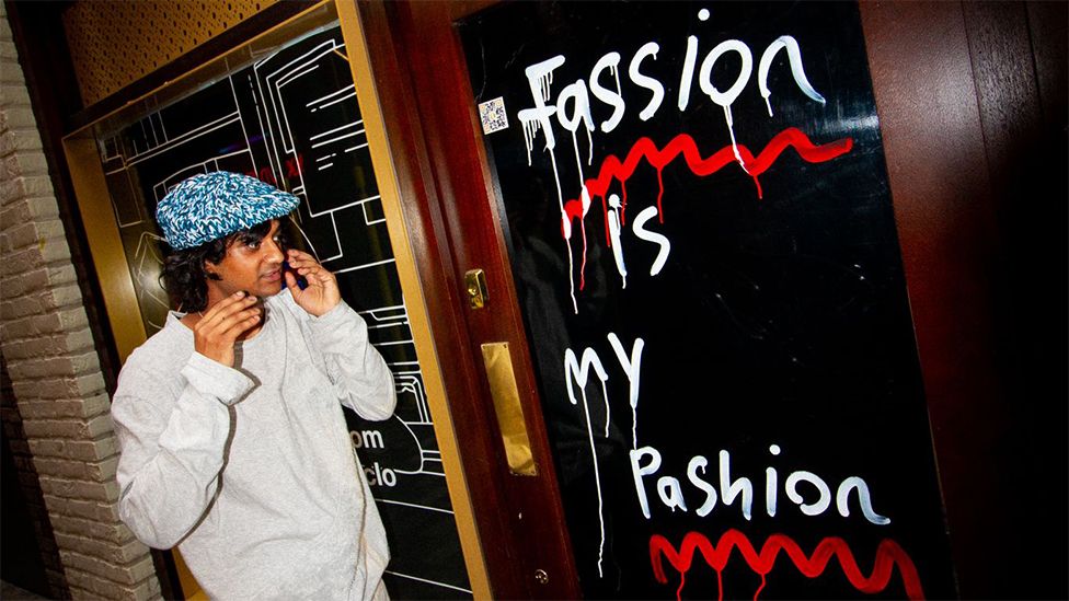 Nav смотрит на произведение искусства с надписью «Моя страсть — это мода»