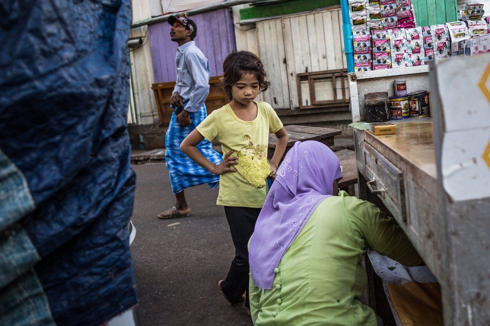 A young girl waits for Thwarhairah to exchange money at her betel nut stand in downtown Yangon, Myanmar, November 2014.