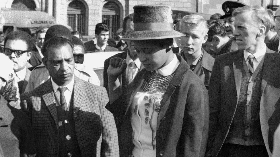 Winnie Mandela leaves the Palace of Justice in Pretoria with her fist clenched, after the verdict of the Rivonia Trial was given