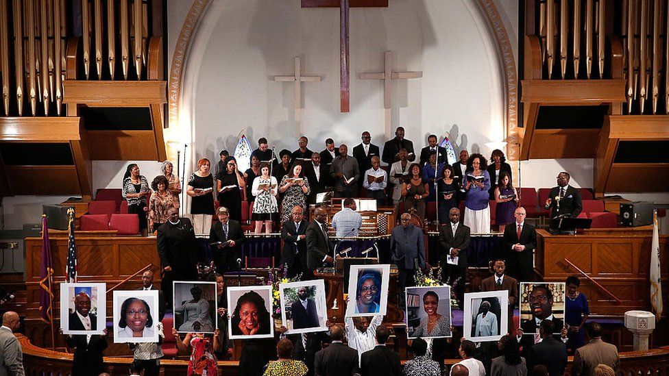 Фотографии девяти жертв, убитых в Африканской методистской епископальной церкви Эмануэля в Чарльстоне, Южная Каролина, держат прихожане во время молитвенного бдения в митрополитской церкви AME 19 июня 2015 г.