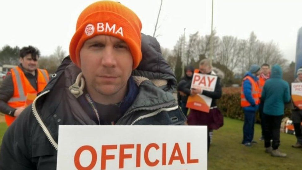 A man in a orange hat at a picket line