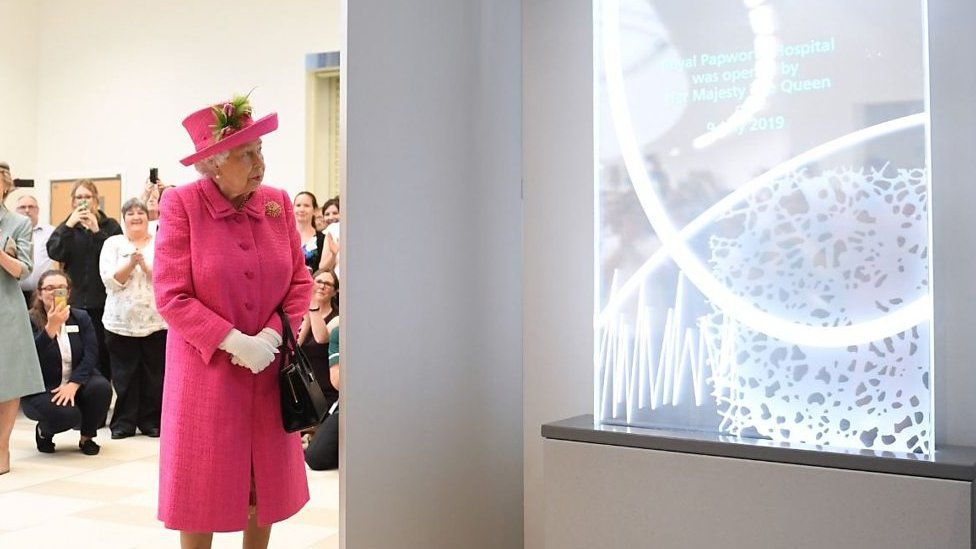 The Queen looks at a plaque