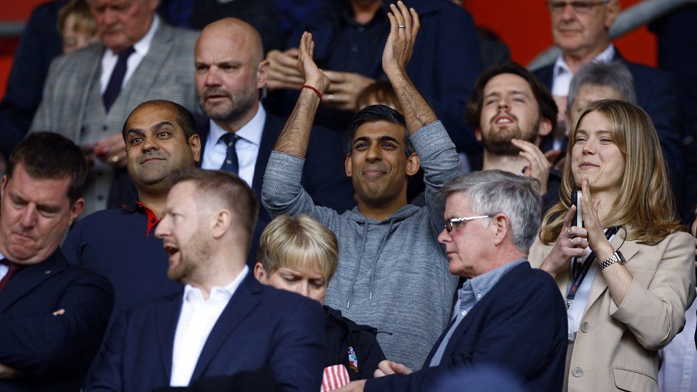 Rishi Sunak in the stand at St Mary's holding his hands above his head to clap