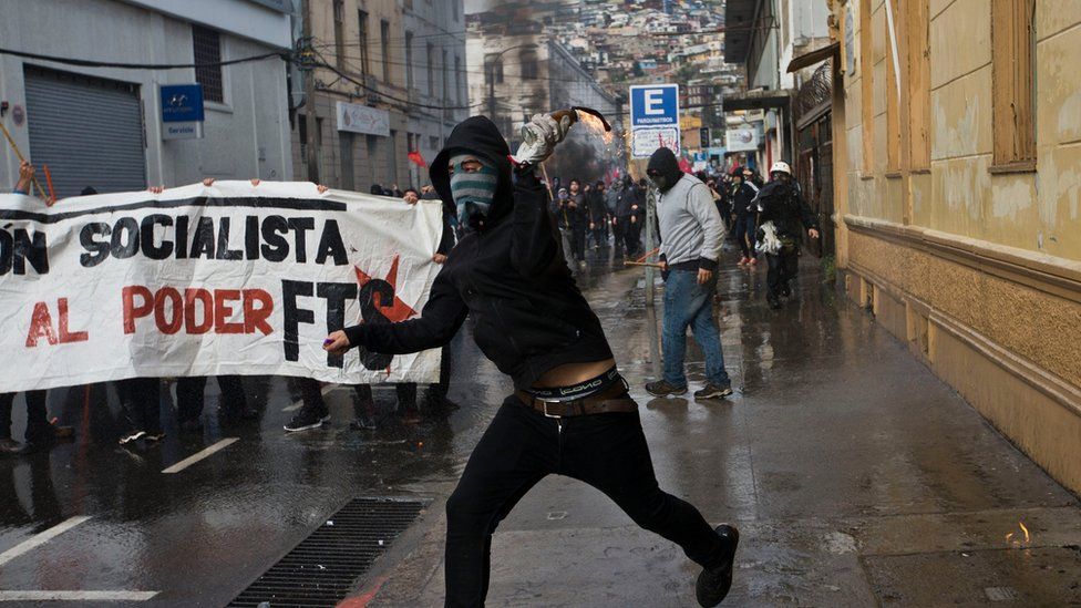 A masked protester launches a Molotov cocktail