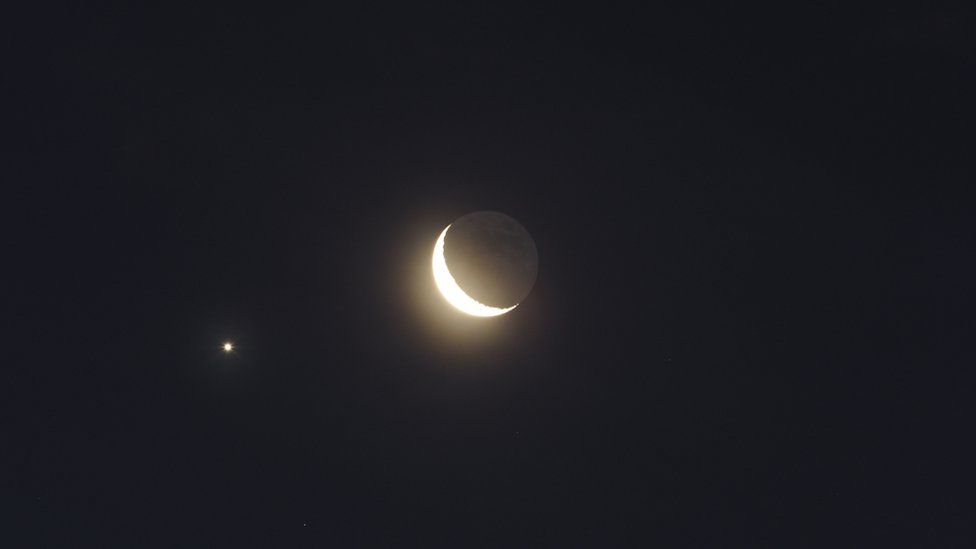 Jupiter captured traveling under the lower left of a Crescent Moon