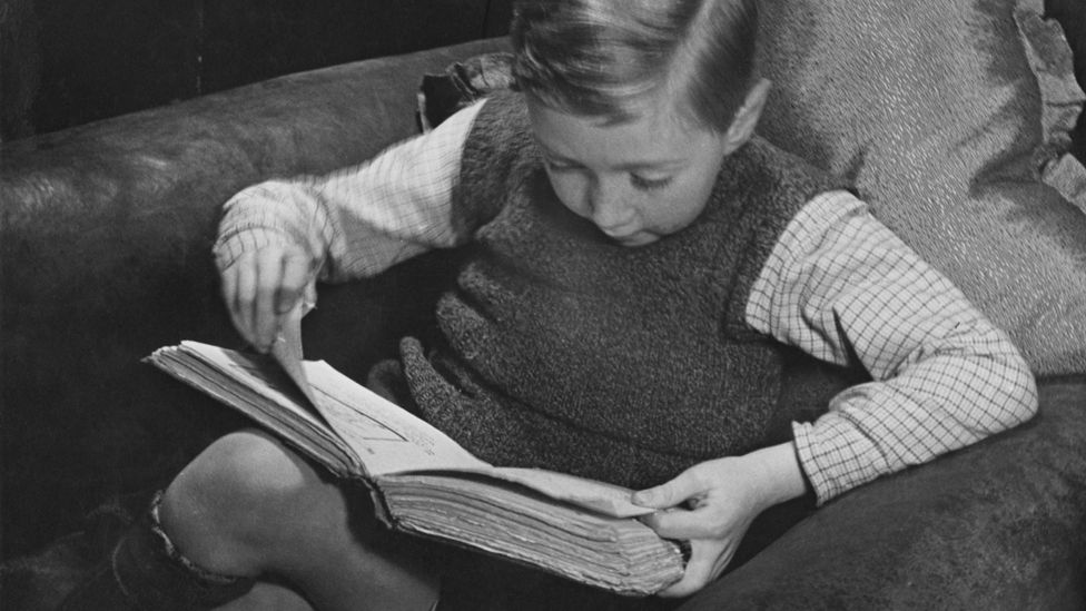 Small boy reading book, 1930s