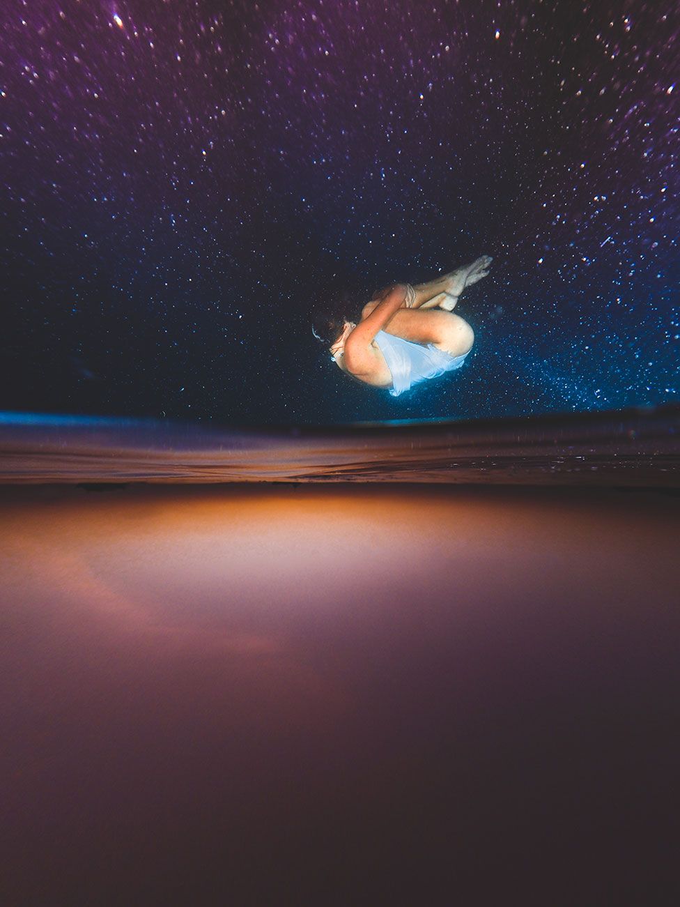 An upside down image of a woman floating in the sea