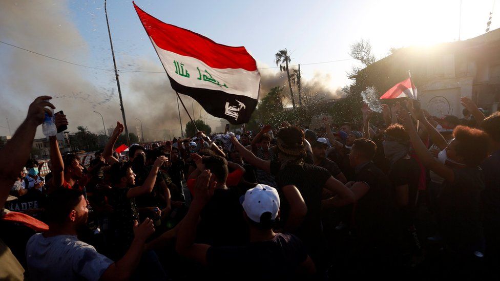 Protesters carrying an Iraqi flag gather near a government building in Basra