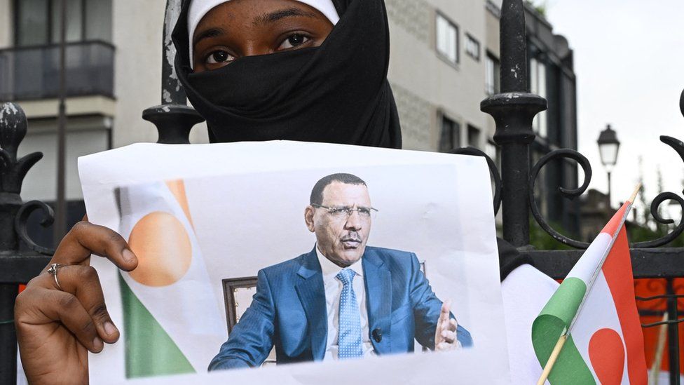 A protagonist  holds an representation  of Mr Bazoum during a rally successful  Niamey