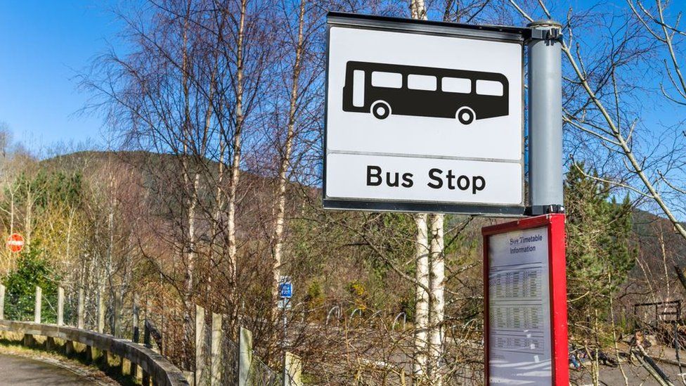 A bus stop sign by a roadside