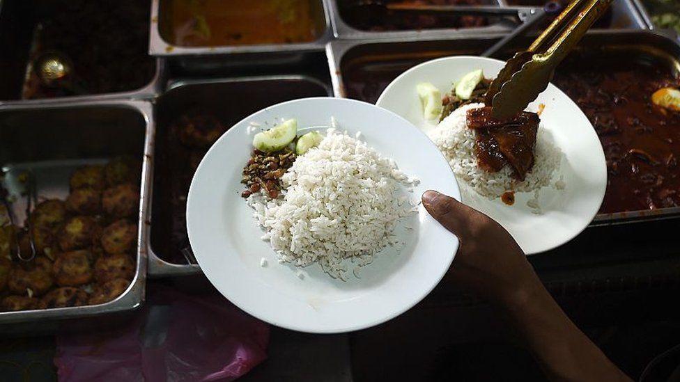 In this picture taken 25 March 2015 a Malaysian stall assistant serves Nasi Lemak dish on a plate at the 'Nasi Lemak Tanglin' stall in Kuala Lumpur