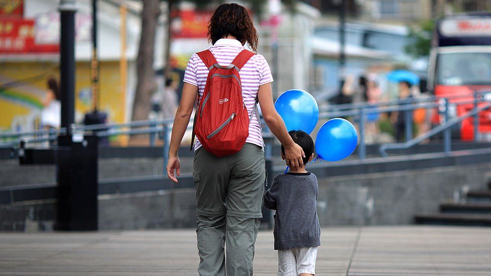A woman walks with a child holding balloons in Hong Kong