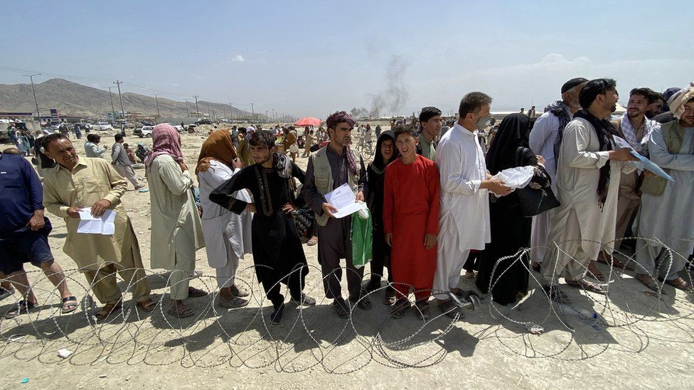 Afghans wait outside the airport in Kabul, trying to flee the country