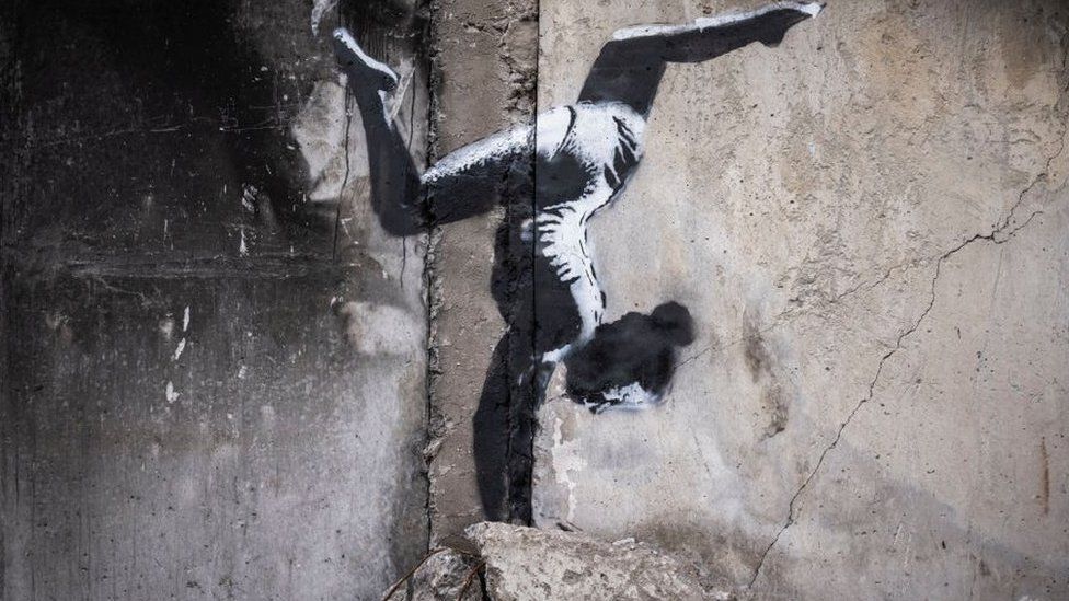 Graffiti of a gymnast doing a handstand painted on a destroyed building in Borodyanka