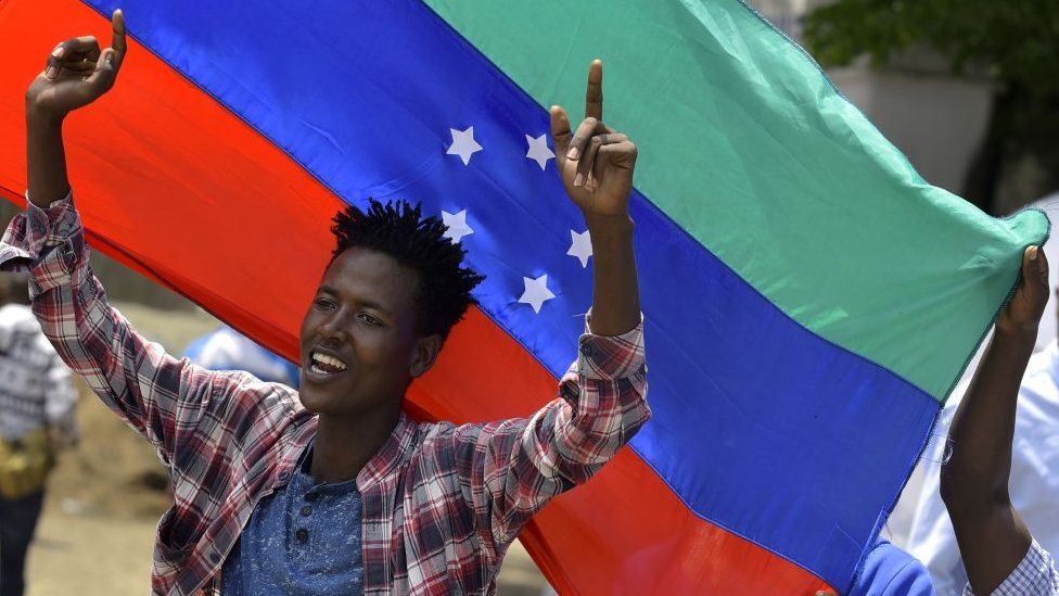 A protester waves the unofficial turqouisem blue and red Sidama flag