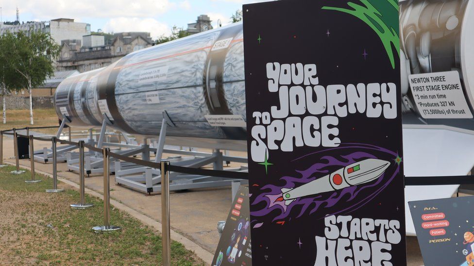 A poster that reads "your journey to space starts here" in front of a model rocket