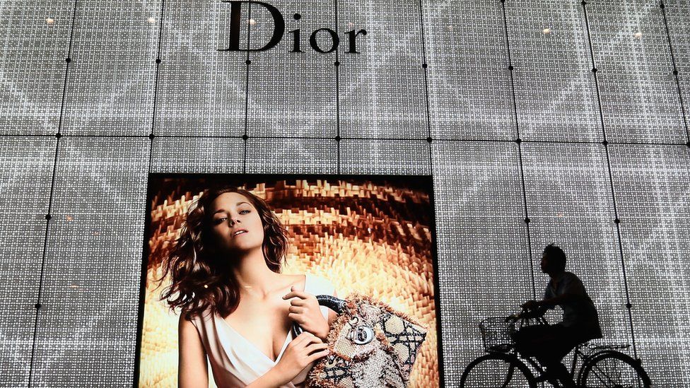 A Chinese man rides bicycle past an advertisement for the Christian Dior store on June 8, 2012 in Beijing, China