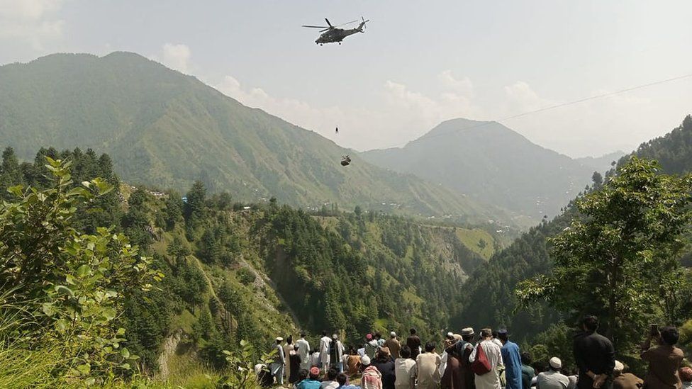 A soldier slings down from a helicopter during a rescue mission to recover students stuck in a chairlift