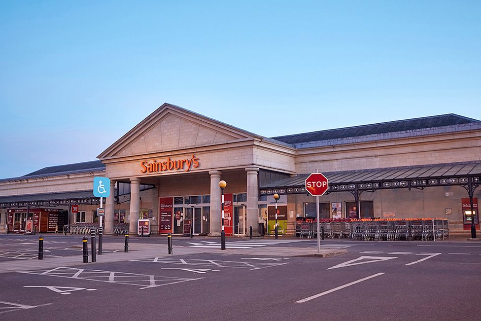 Вид на фасад супермаркета Sainsbury и пустую автостоянку