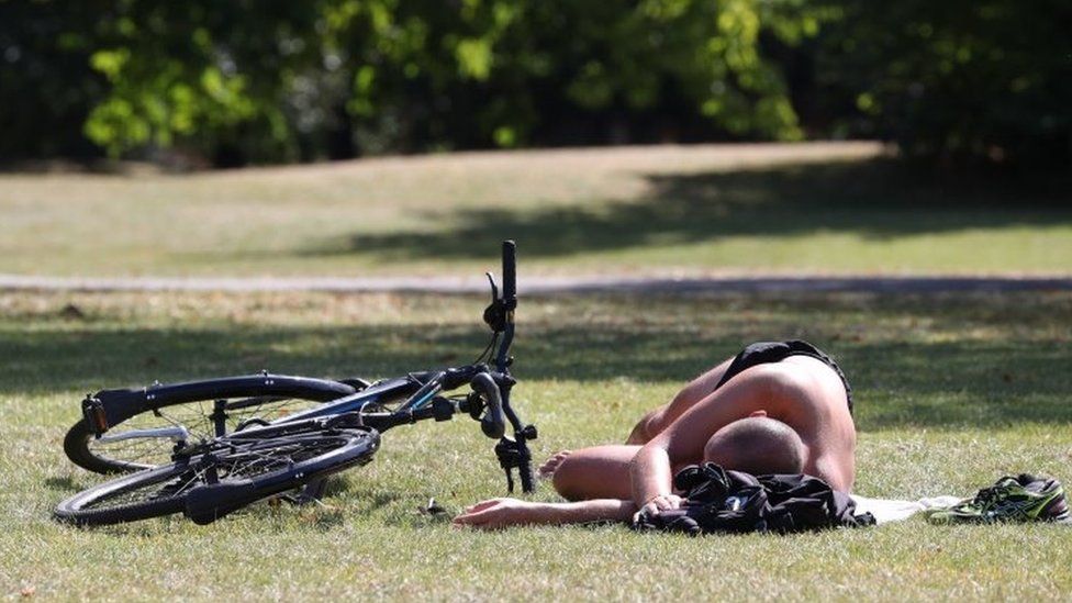A man sunbathes next to his bicycle in Regent"s Park, London