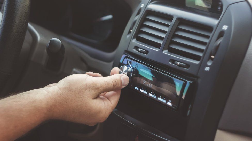 Picture of a hand turning a car radio