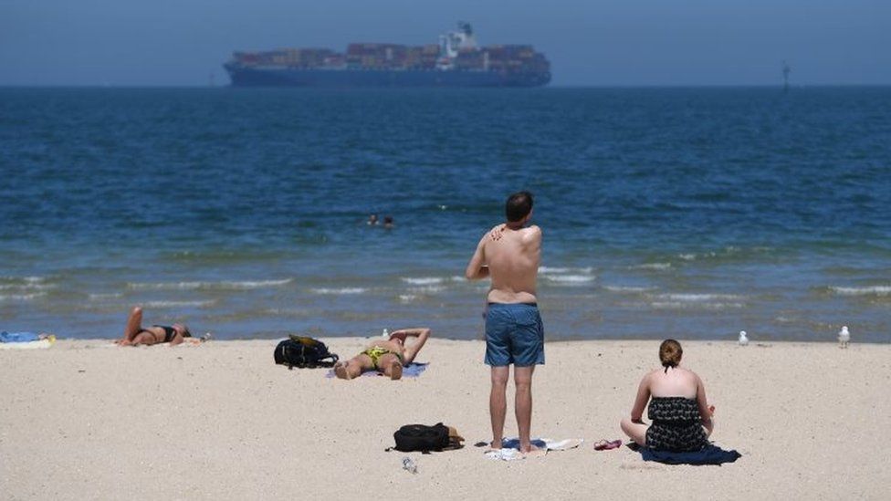 Beachgoers apply sunscreen on a hot day in Melbourne