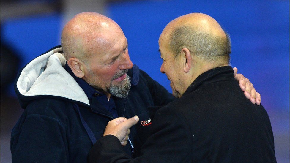 French Defence Minister Jean-Yves Le Drian (R) embraces Serge Lazarevic (L), France's last remaining hostage after landing at the Villacoublay military base near Paris, France on December 10, 2014.