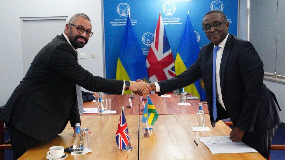 Home Secretary James Cleverly shakes hands with the Rwandan Minister of Foreign Affairs.