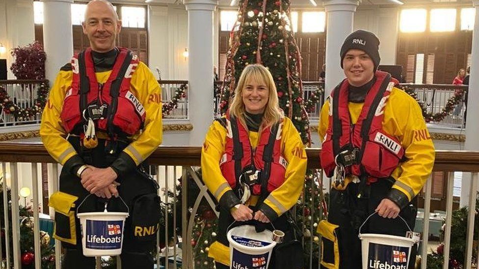 Sarah and two male RNLI colleagues collecting donations for the RNLI in a shopping centre