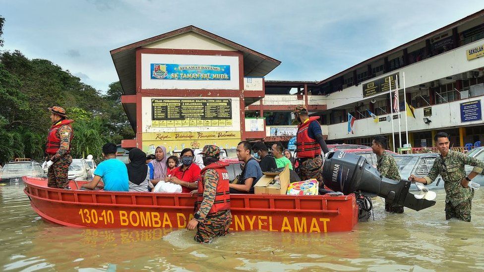 Rescue officials evacuate people in a boat in Shah Alam, Selangor on December 20, 2021, as Malaysia faces some of its worst floods for years.