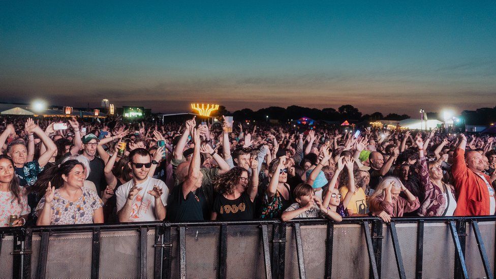 Festivalgoers at FORWARDS at the front close to the barrier with lights in the background