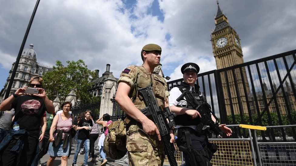 An armed soldier and an armed police officer patrol outside the Houses of Parliament on May 24, 2017 in London