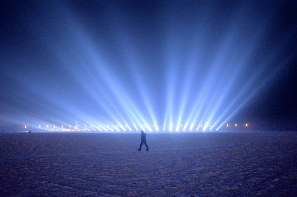 A man walks on the frozen Songhua river beside the Harbin international ice and snow festival