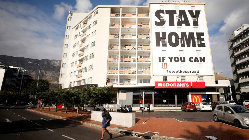 Man walks past a stay at home poster