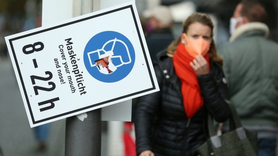 People walk past a sign reading "Mask is mandatory" on a shopping street as the spread of coronavirus disease continues in Frankfurt, Germany, October 19, 2020