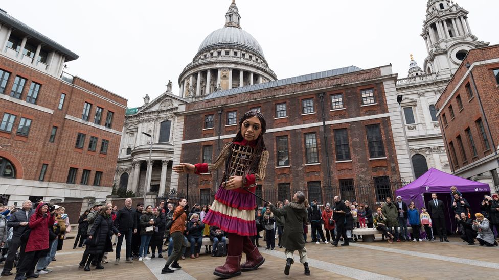 Little Amal is welcomed by passers-by at Paternoster Square