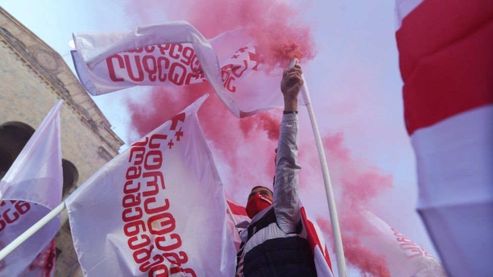 An opposition supporter holds a flare during a rally against the results of a parliamentary election in Tbilisi, Georgia