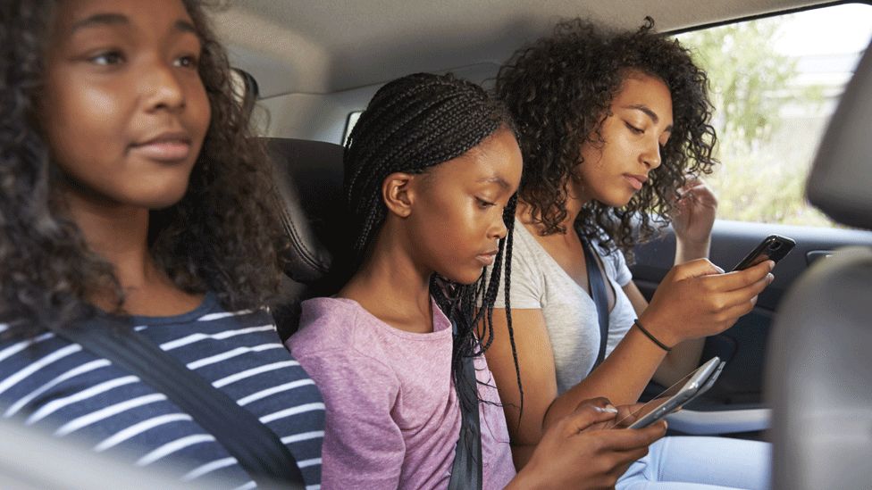 Girls in car with two out of three on phones