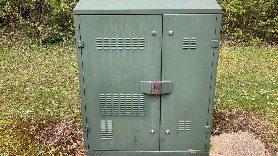 Green metallic cabinet in a grass verge