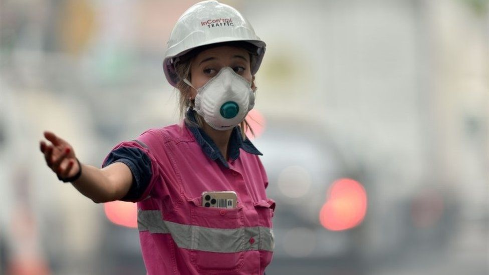 A traffic coordinator on a construction site wears a mask to protect against smoke pollution in Sydney on December 10, 2019.