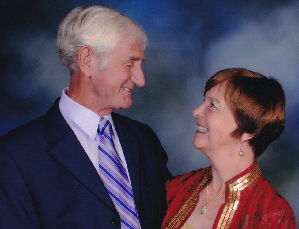 An older couple on their 50th wedding anniversary smile at each other