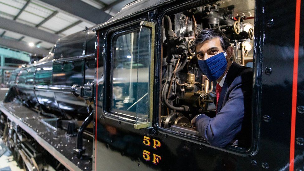 Rishi Sunak, wearing a face mask, pictured on a locomotive in 2021