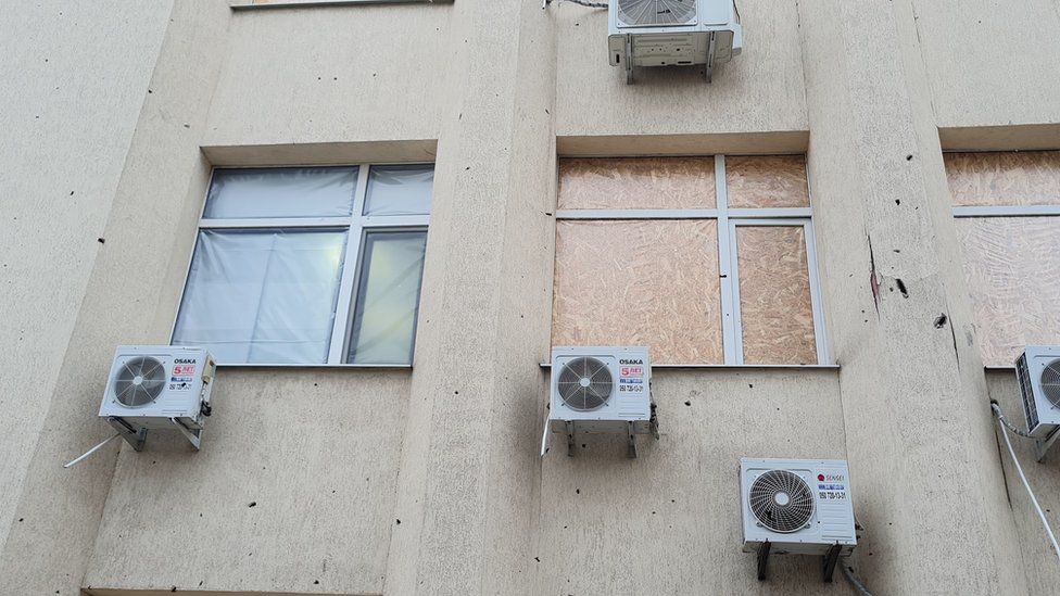 Bullet damaged windows in Ukraine, with one repaired by Insulate Ukraine