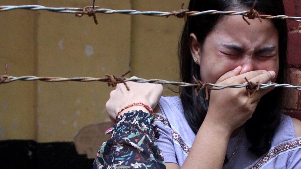 Chit Suu Win, wife of Reuters journalist Kyaw Soe Oo, is seen crying behind barbed wire after the verdict